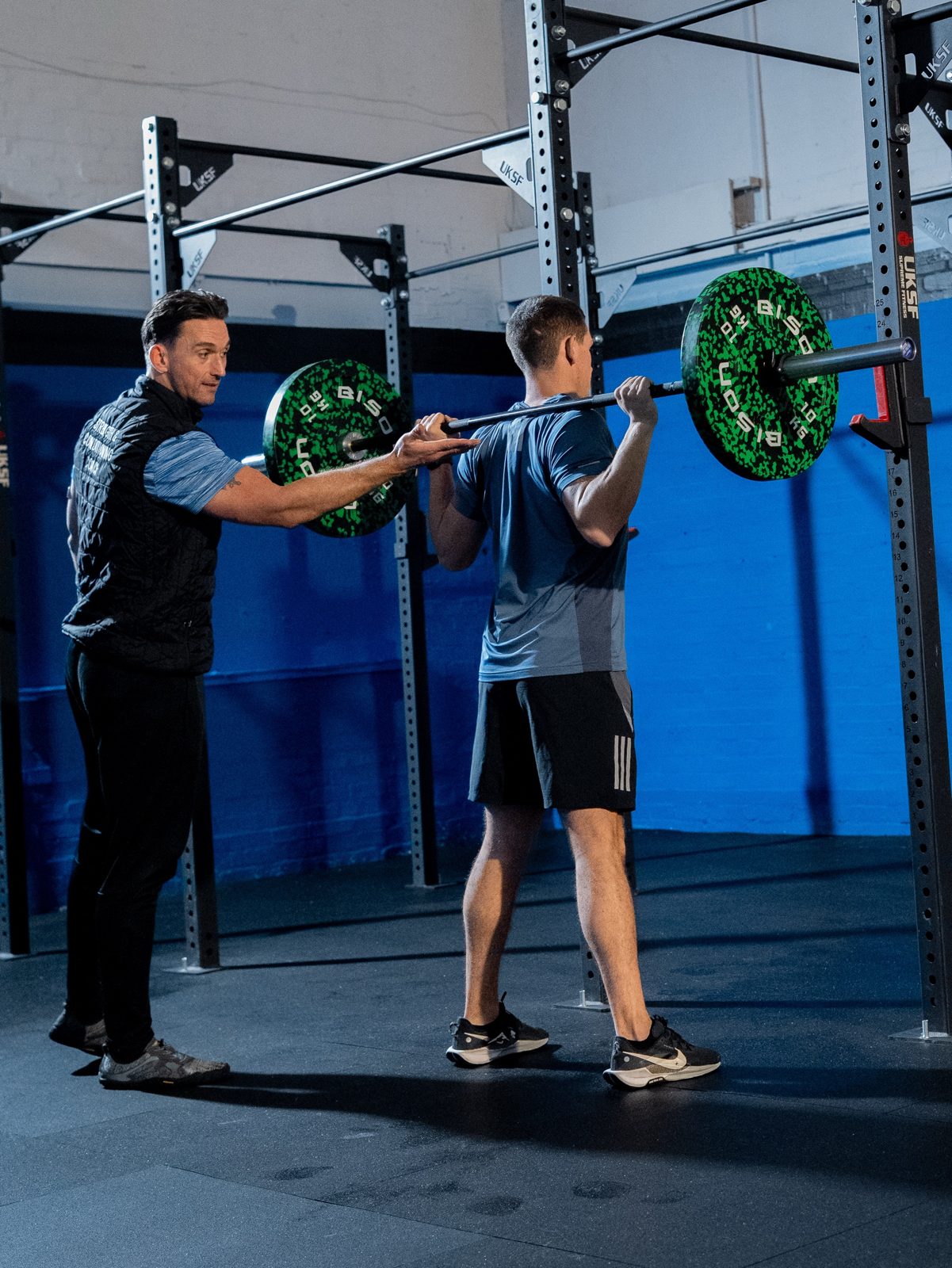 Coach Craig cueing a member's back squat at the rack